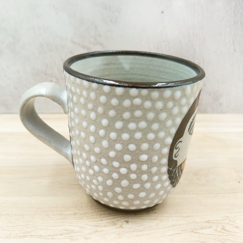 Grey mug with face and orange design