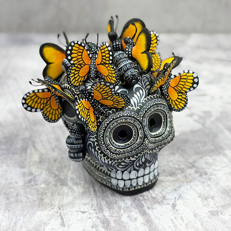 Cráneo blanco y negro con mariposas monarca