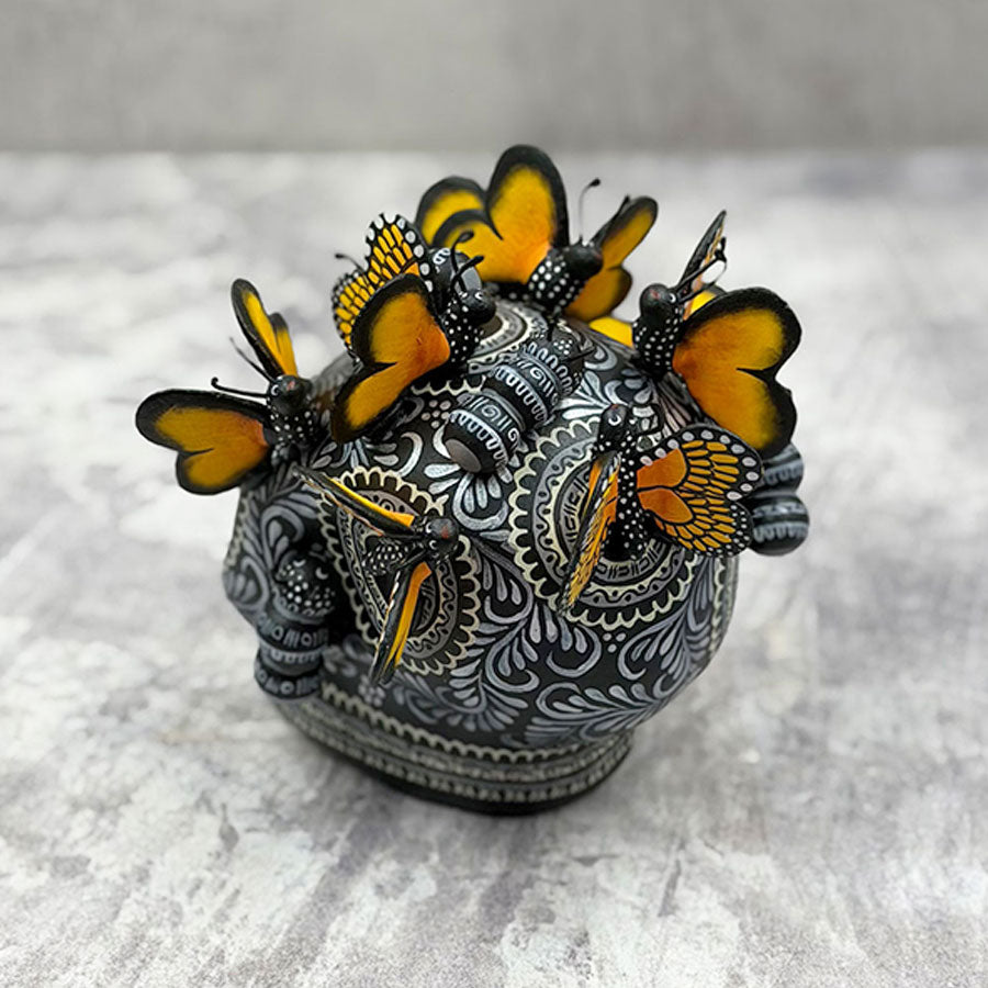 Cráneo blanco y negro con mariposas monarca
