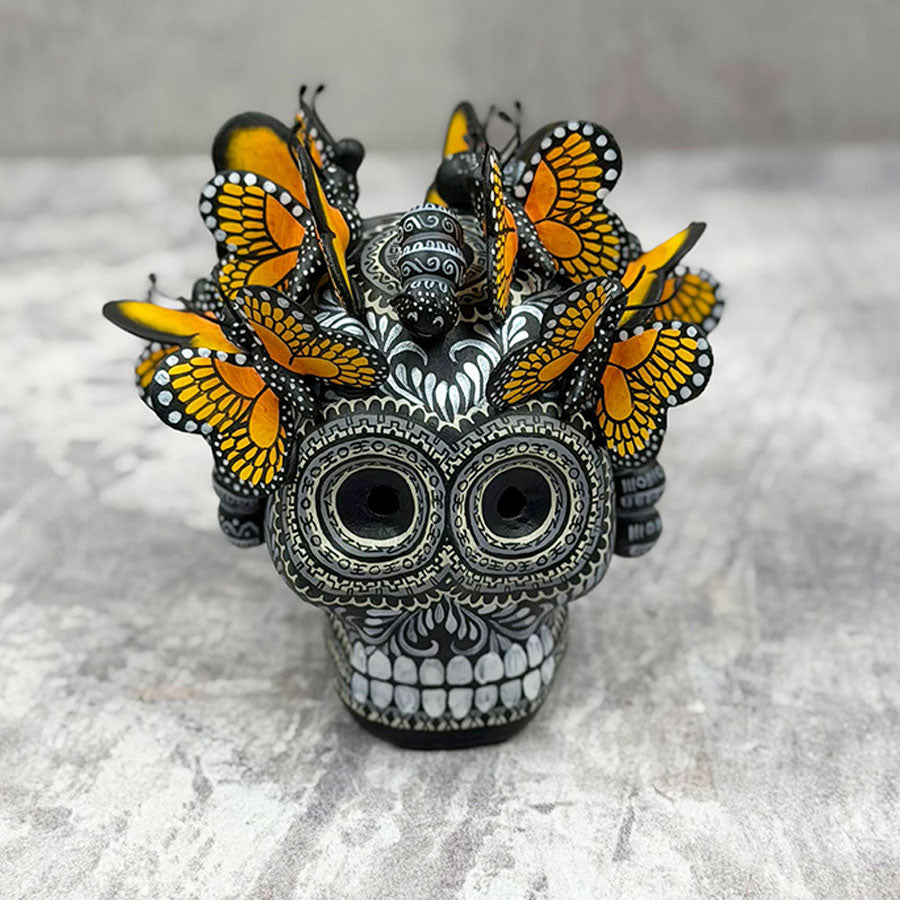 Cráneo blanco y negro con mariposas monarca