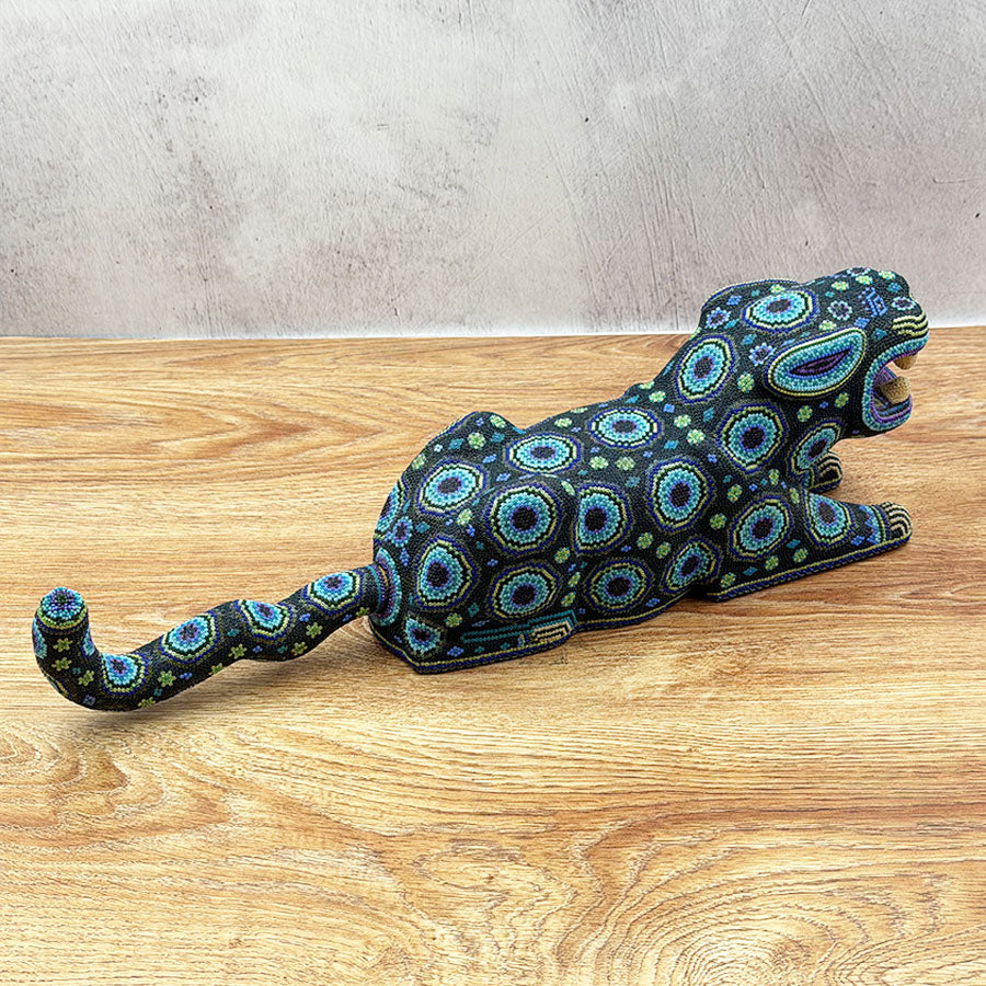 Blue jaguar lying down with Huichol design