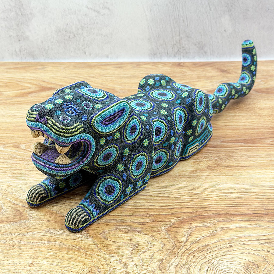 Blue jaguar lying down with Huichol design
