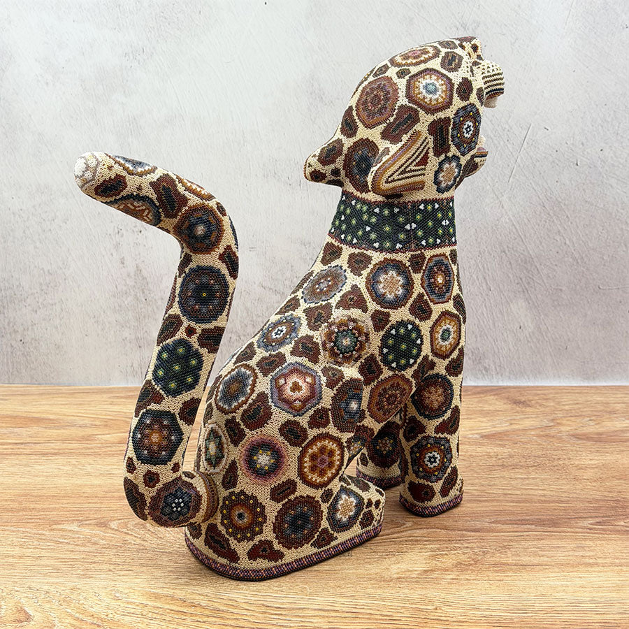 Brown jaguar sitting with Huichol design