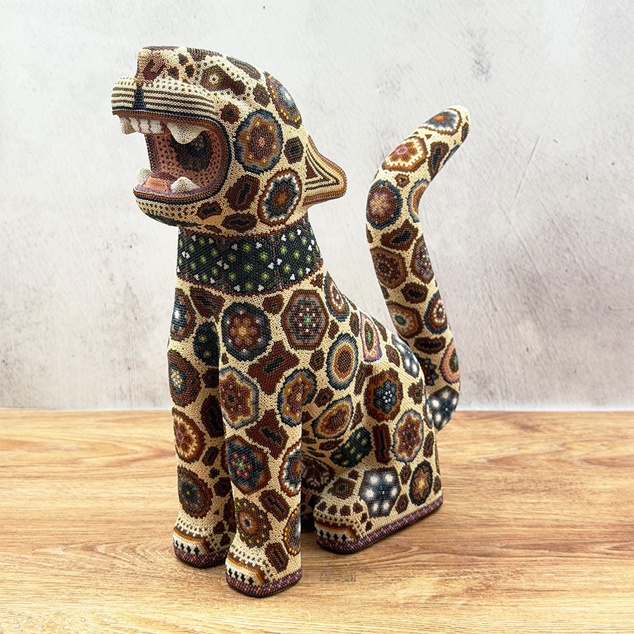 Brown jaguar sitting with Huichol design